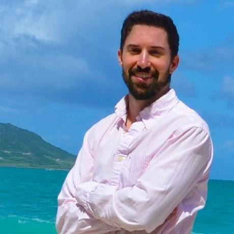 Clark Whitehead smiling beside the ocean, with mountains in the background